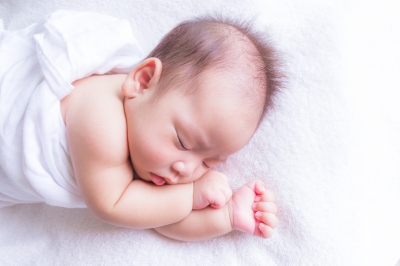 Newborn baby sleeping on a white blanket.