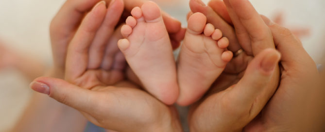Детские ножки в руках родителей