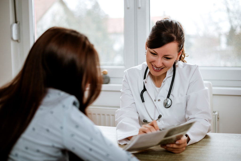 Médico sorridente dando notícias felizes a um paciente.