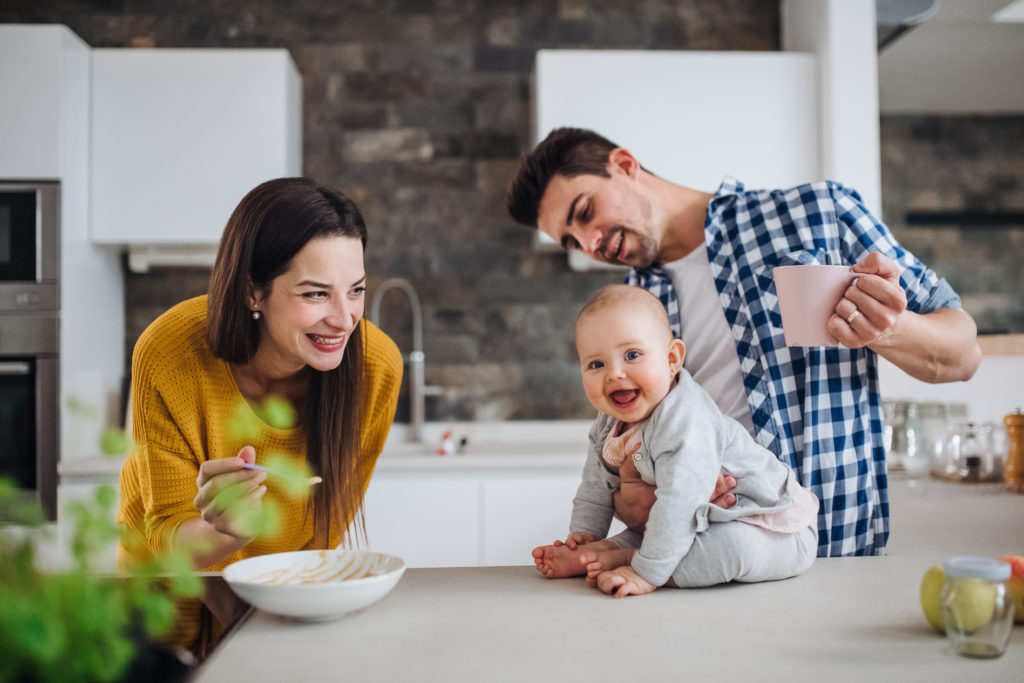 Gelukkige familie met een baby in een moderne keukenomgeving.
