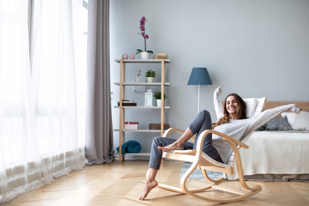 Mujer feliz descansando cómodamente sentada en una silla moderna