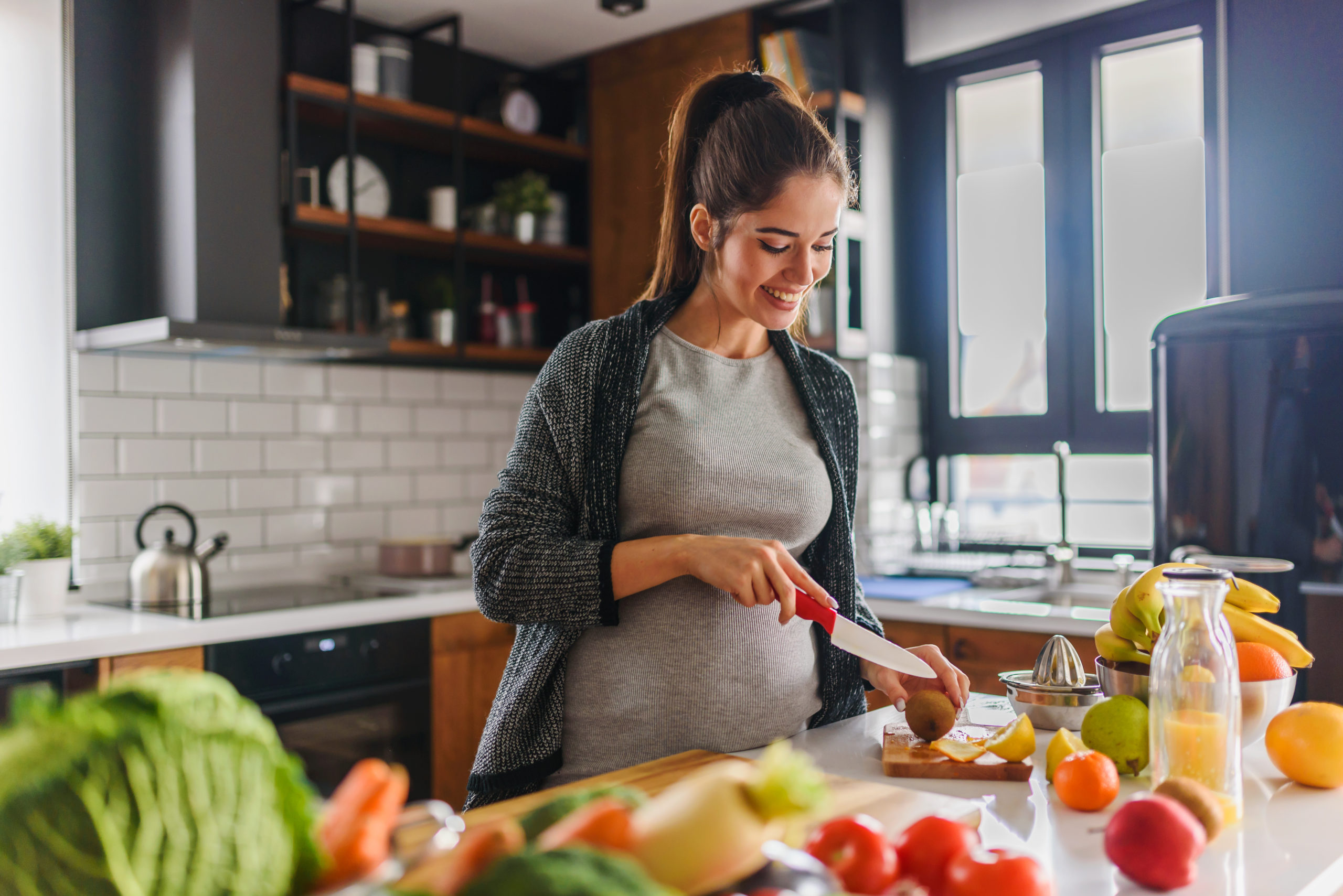 Beautiful smiling young pregnant woman preparing healthy food