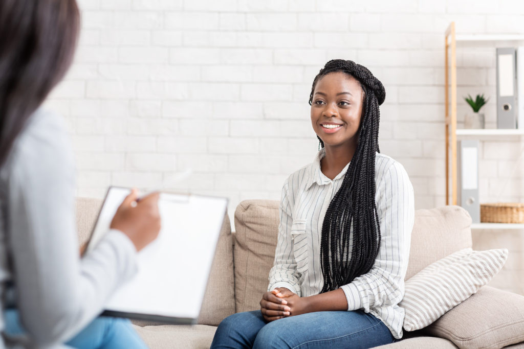 Mujer negra feliz sentada en la oficina