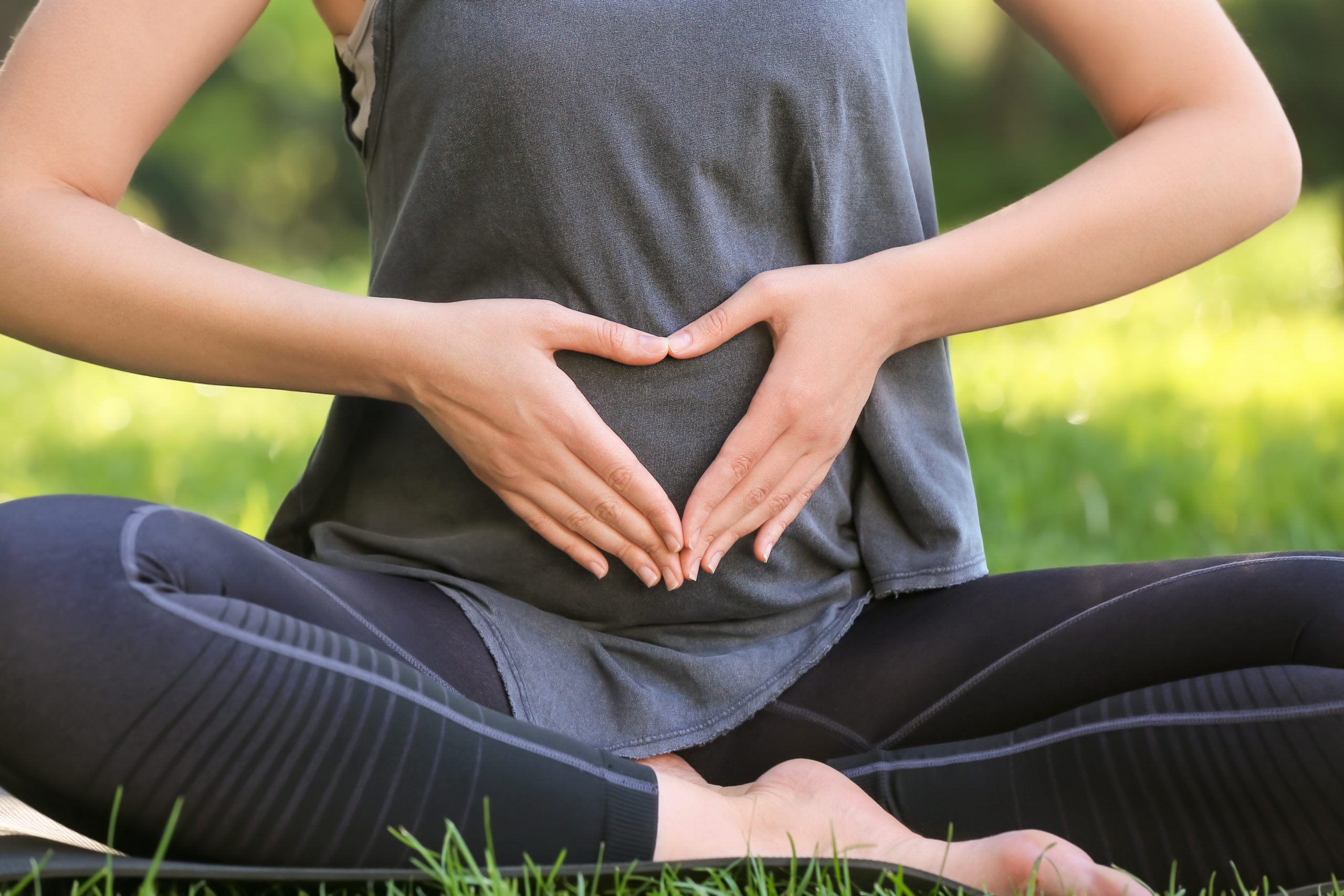 Junge schwangere Frau praktiziert Yoga im Freien, Nahaufnahme