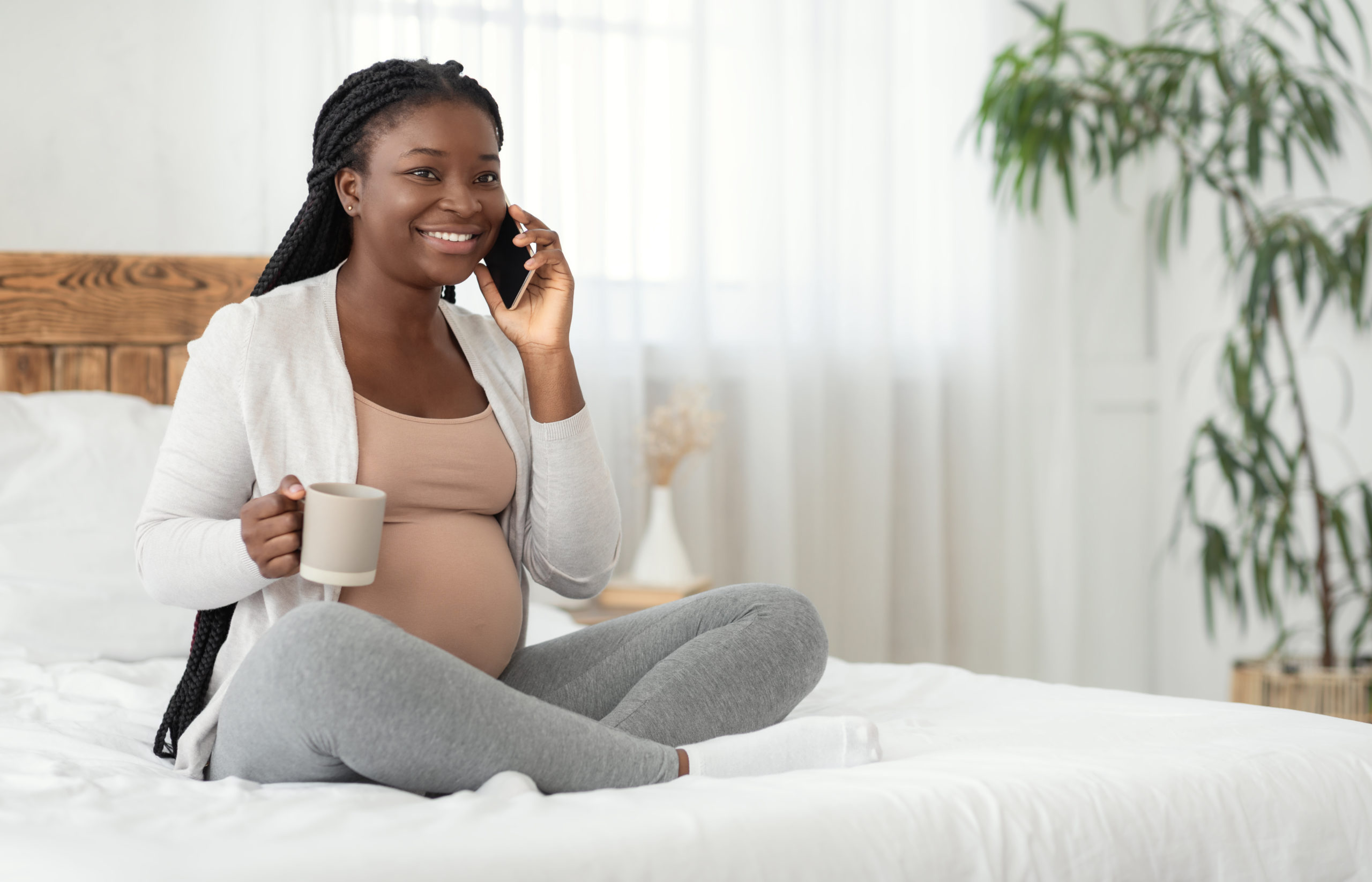 Pregnant Pastime. Smiling Black Expectant Mother Talking On Cellphone And Drinking Tea Smiling Black Expectant Mother Talking On Cellphone