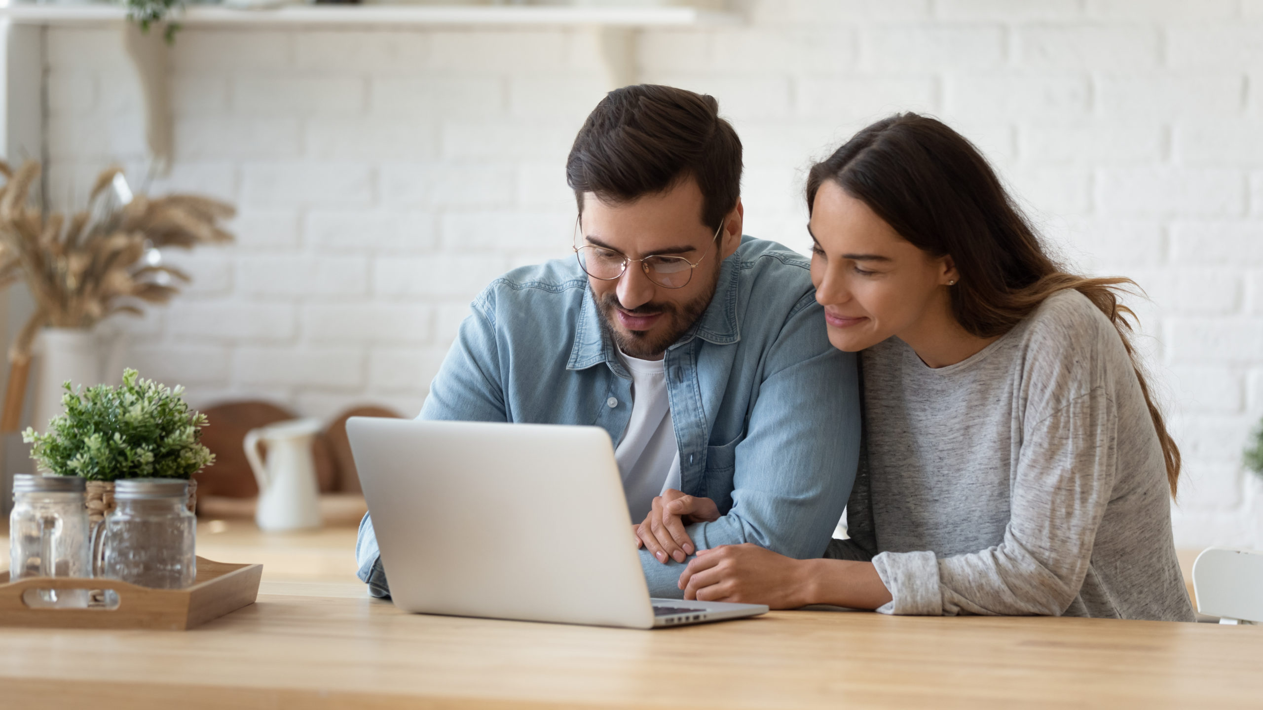 Casal pesquisando opções de barriga de aluguel em um laptop.