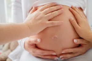 Hände tasten den Babybauch